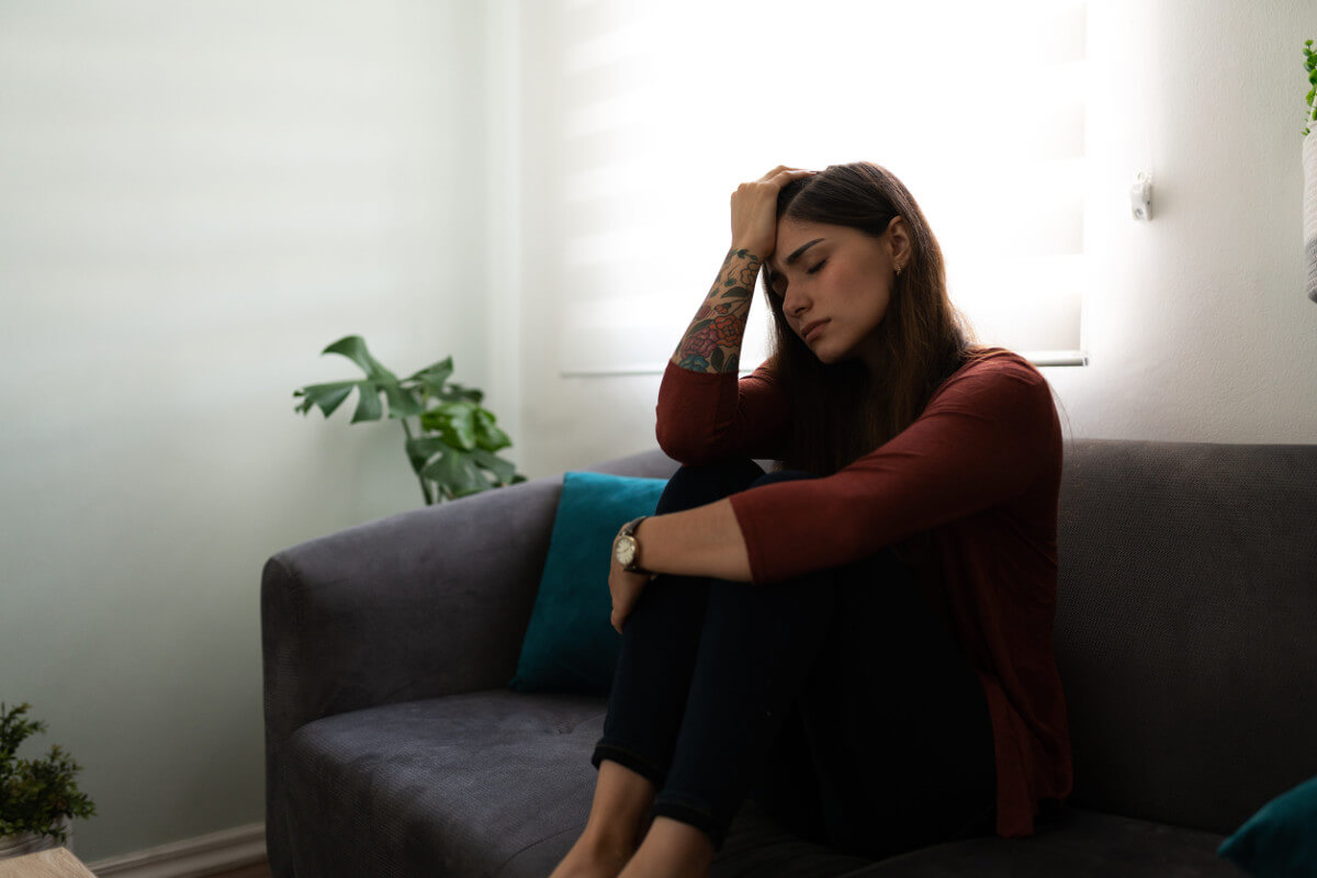 Young woman looking sad and melancholic sitting on couch