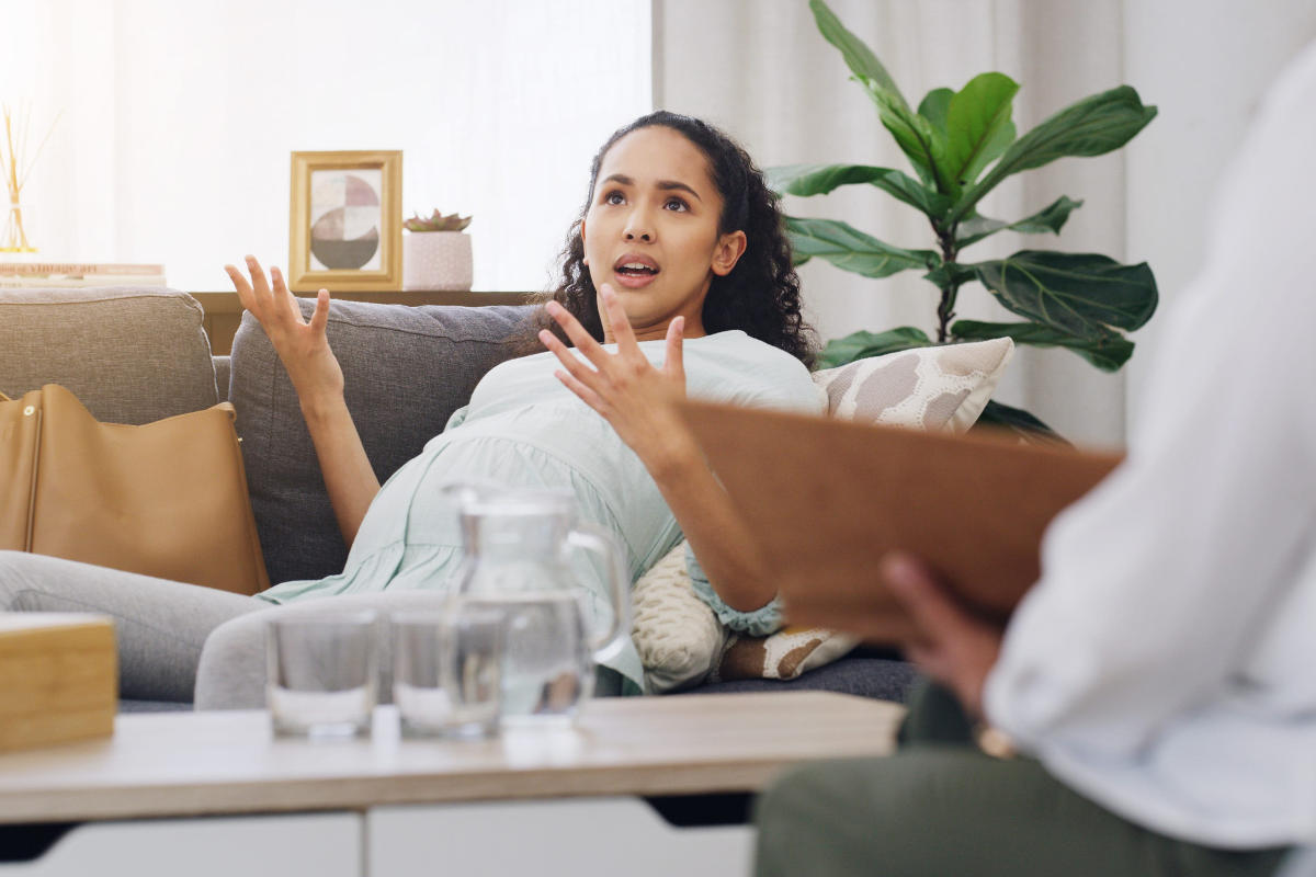 Pregnant woman lying on couch talking to therapist in office