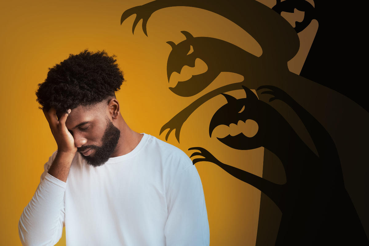 Stressed man touching head afraid of ghost monsters behind him
