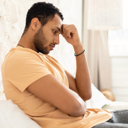 Unhappy man sitting in bedroom