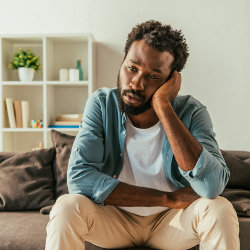 Thoughtful man sitting on couch at home