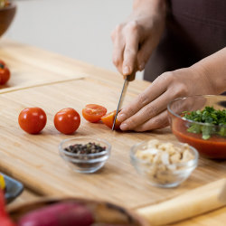 Woman chopping fresh cherry tomatoes for salad