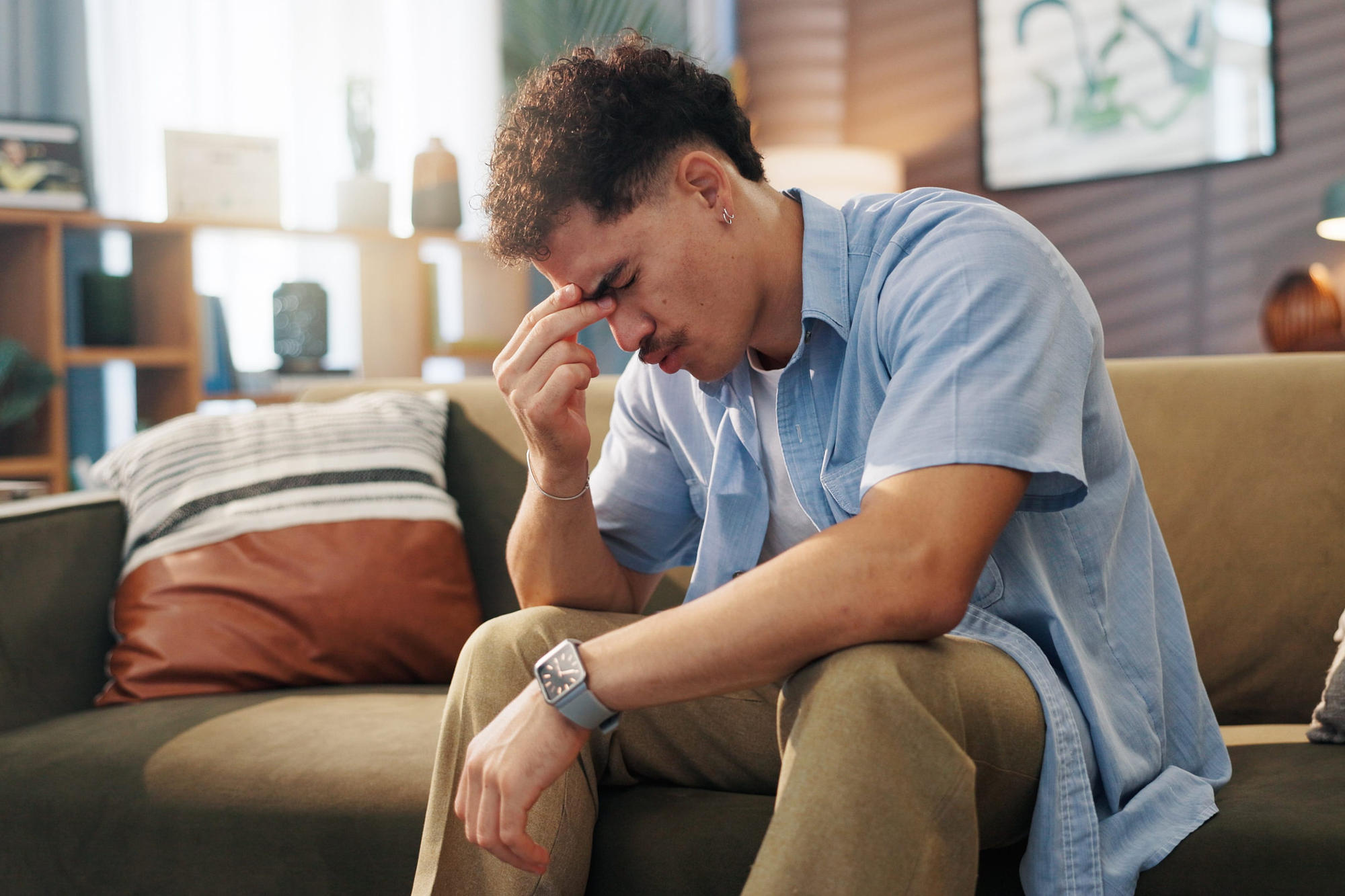Stressed man on sofa at home experiencing worry and frustration