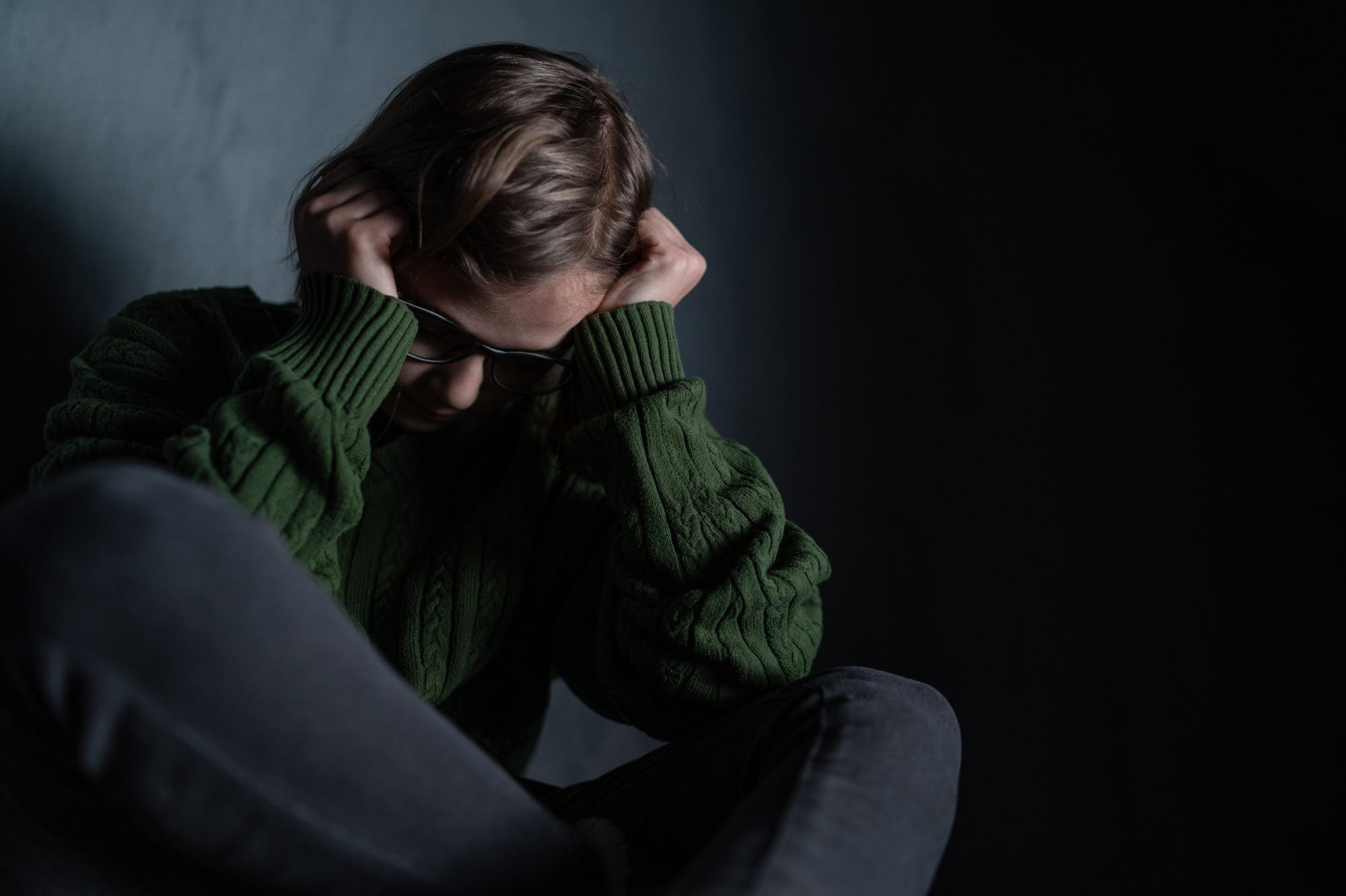 Sad little girl alone in darkness covering face