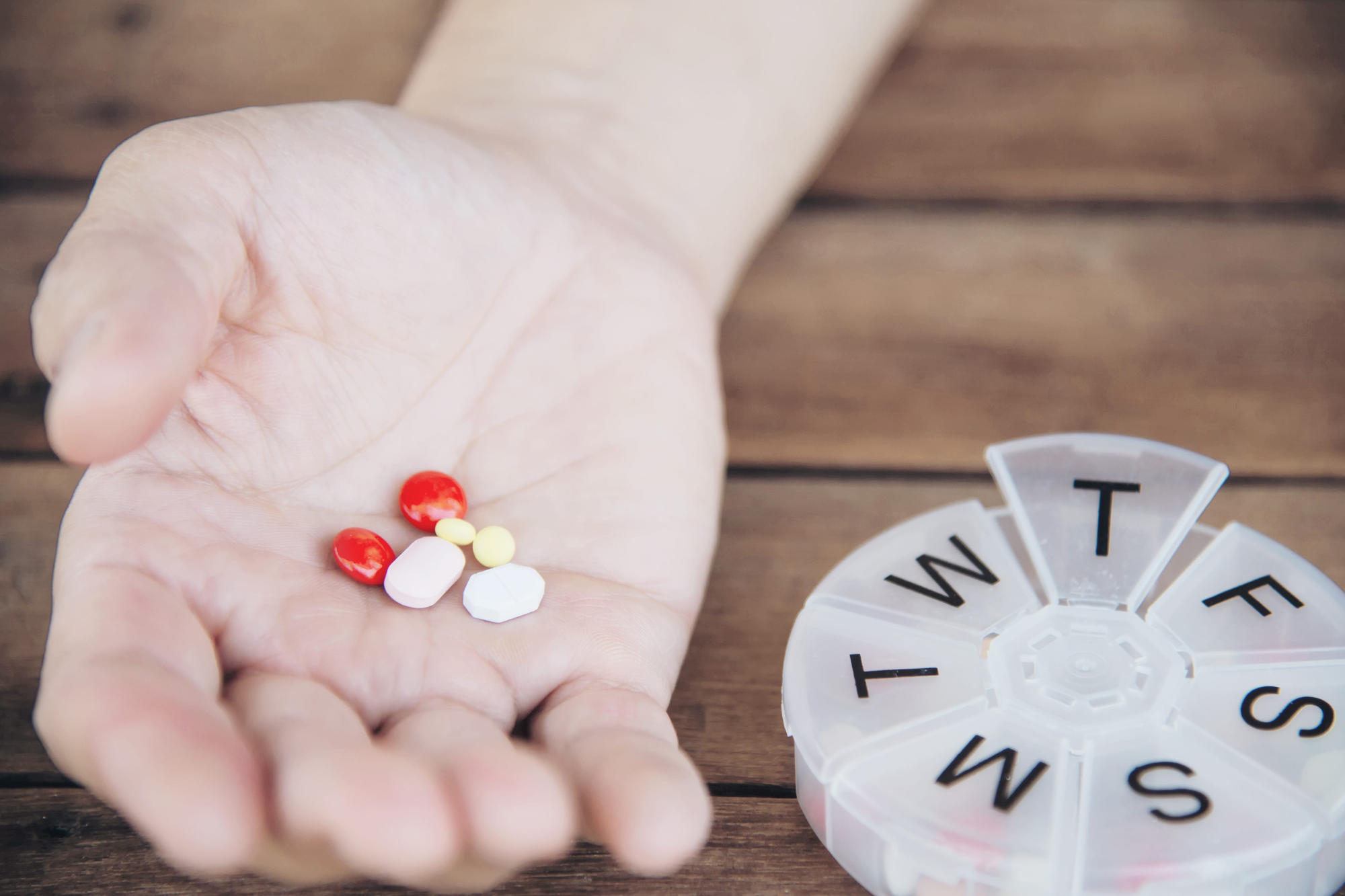 Person holding medication to be placed in a pill organizer