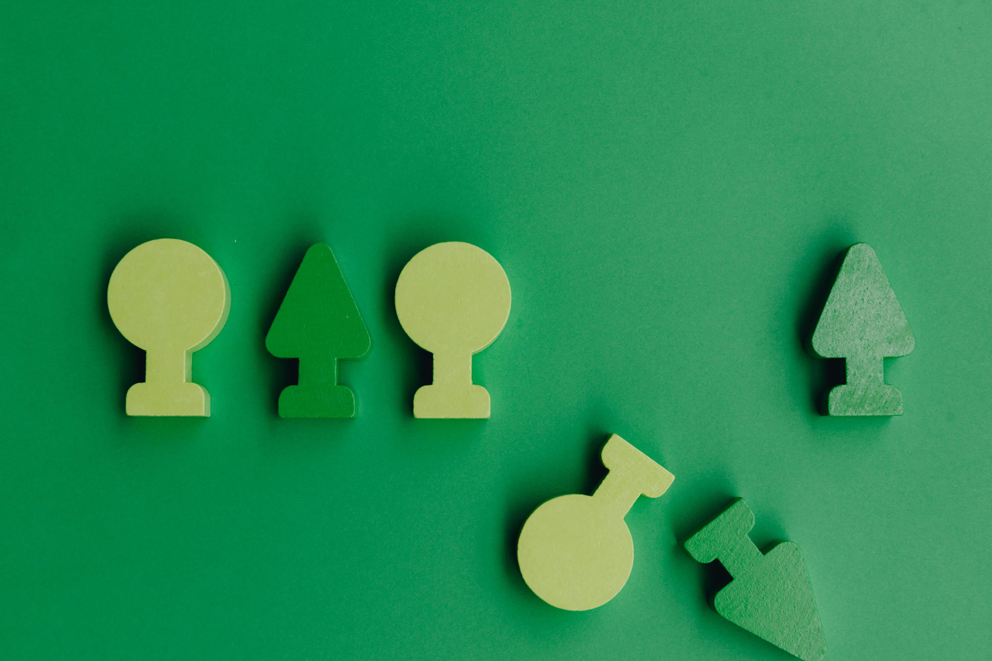 Wooden blocks shaped like trees, against green backdrop