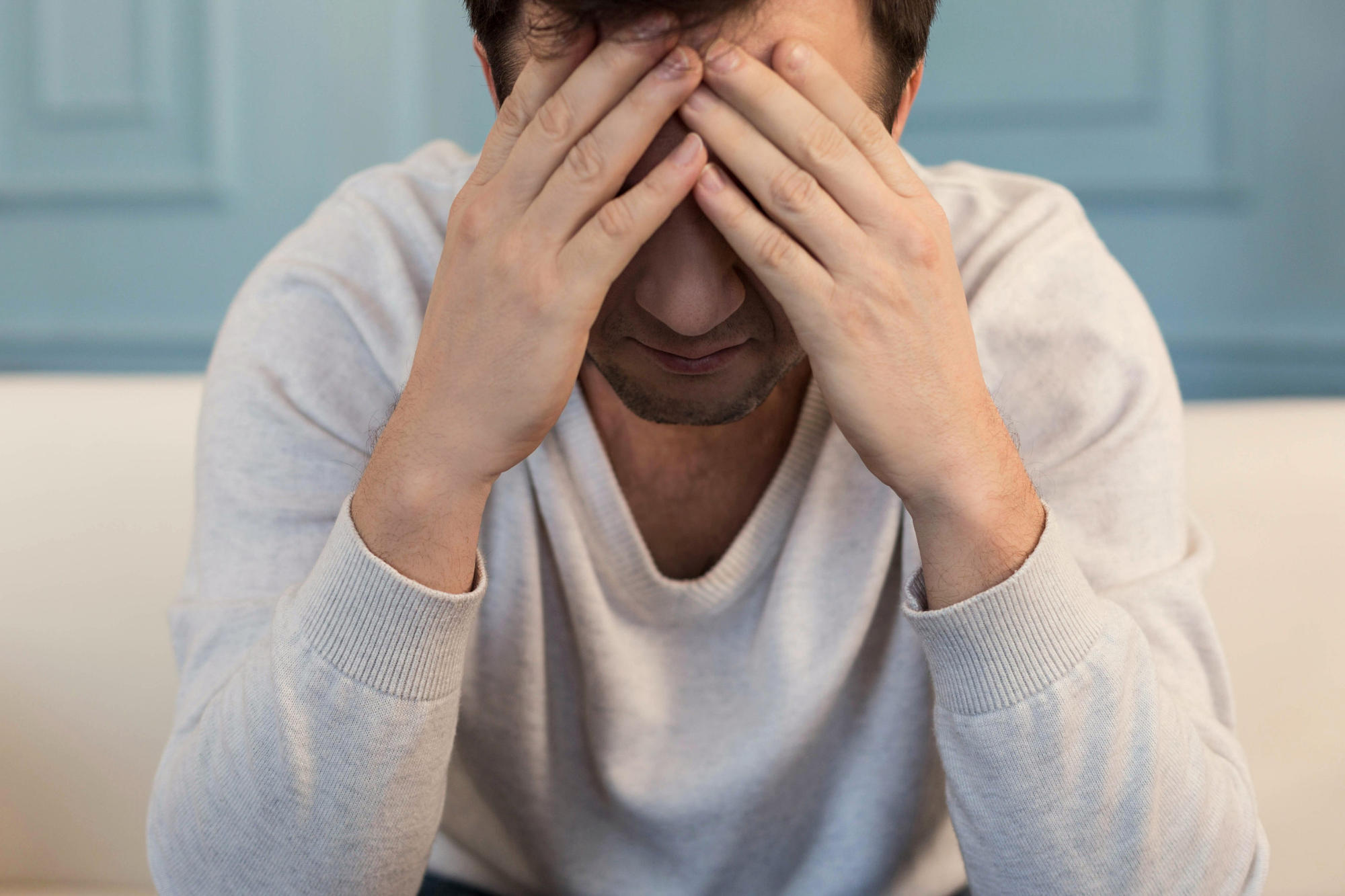 Sitting man covering face with hands