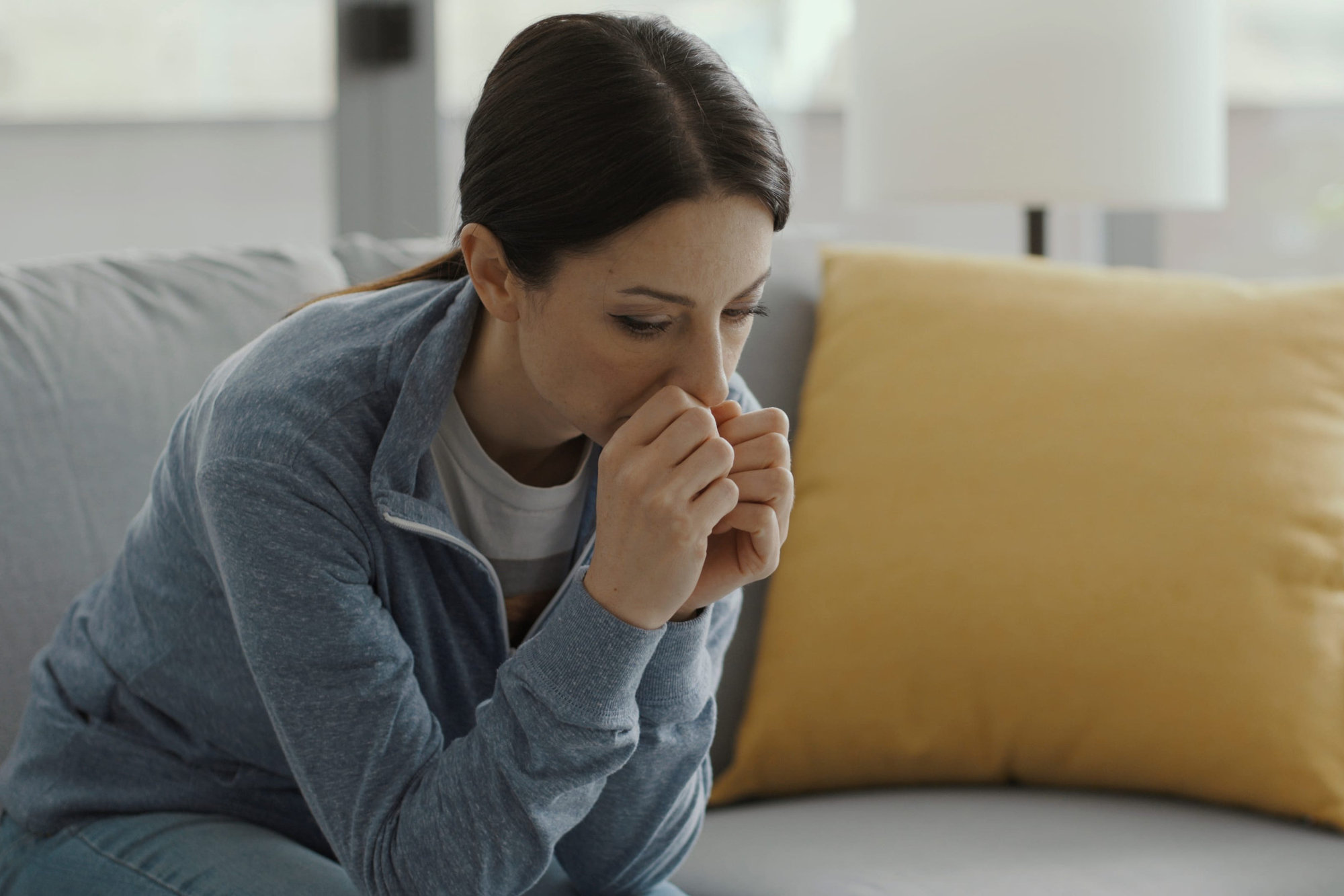 Sad woman sitting on couch at home