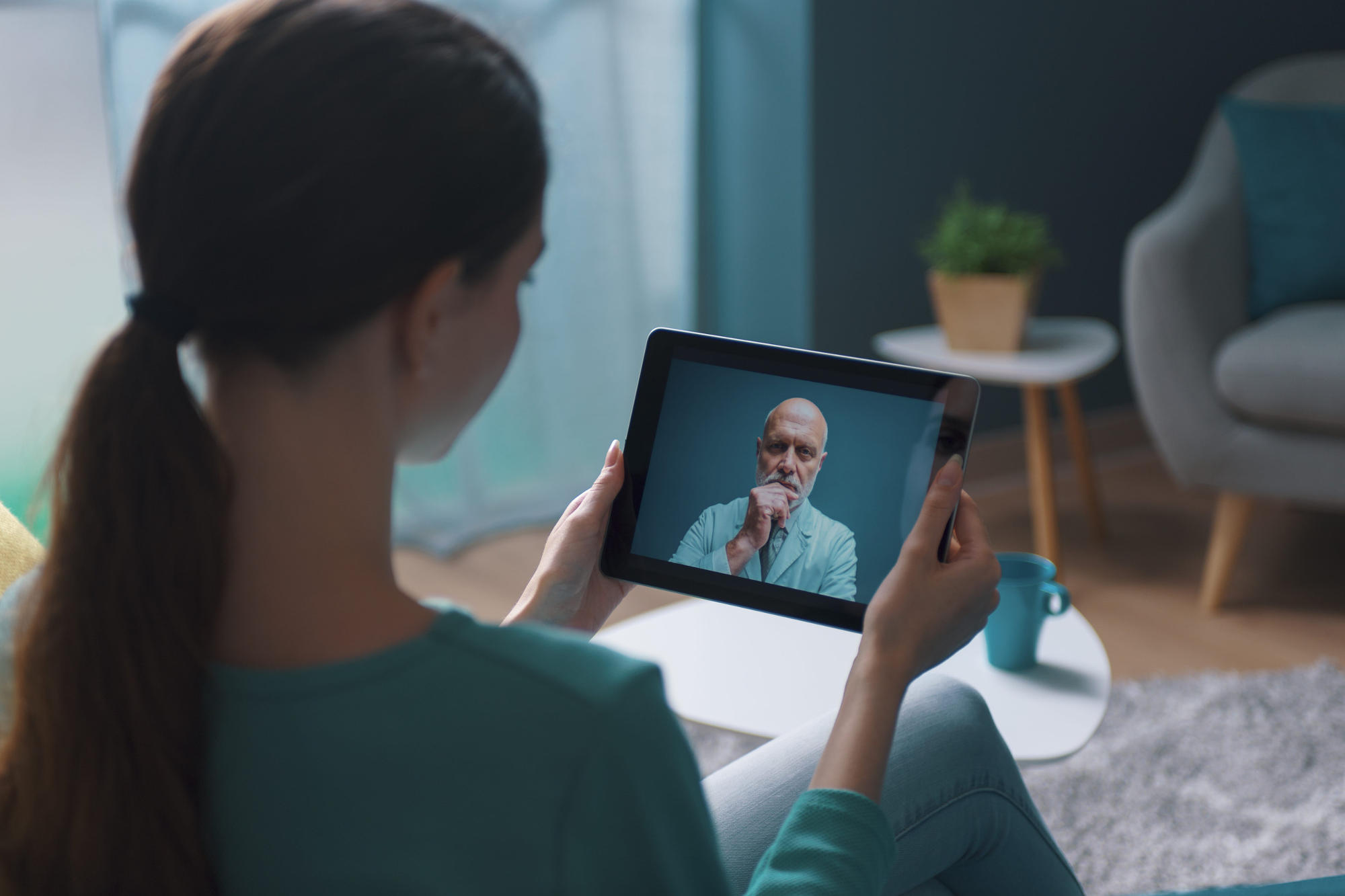 Woman having medical consulation with her doctor over a video call on her tablet 