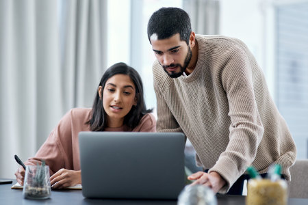 Young man and woman using laptop while working together
