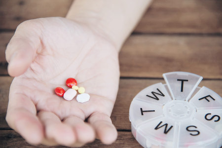 Person holding medication to be placed in a pill organizer