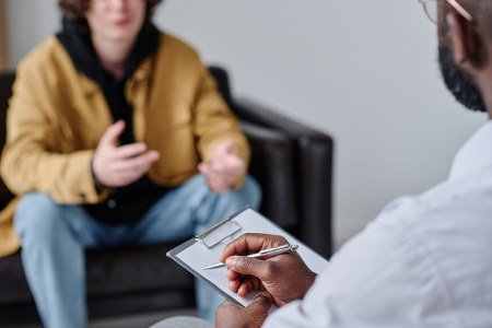 Psychologist listening to patient and making notes during therapy session