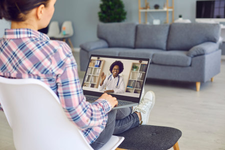 Young woman talking to doctor via video call on laptop