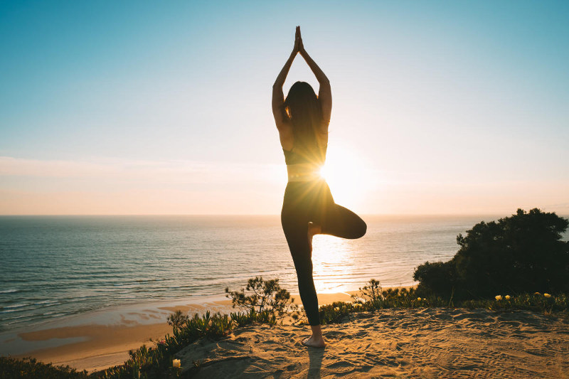 Woman practicing yoga at sunset