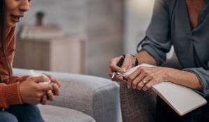 An image showing a patient crying and seeking help from a female psychologist during a therapy session for depression, while discussing trauma.