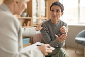A distressed mature woman is listening to a female psychologist who specializes in adult psychiatry, focusing on mental health support.