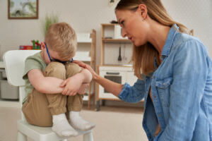 A sad little boy is being consoled by an ADHD specialist and therapist.