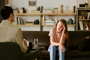 Young Caucasian Woman Sitting on Sofa Discussing Depression Symptoms with Therapist During Depression Therapy.