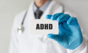 Doctor holding a card with text ADHD.