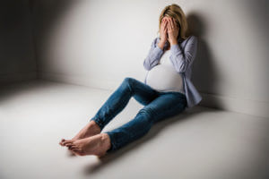 A pregnant woman experiencing high levels of stress and symptoms of perinatal depression, isolated against a white background.